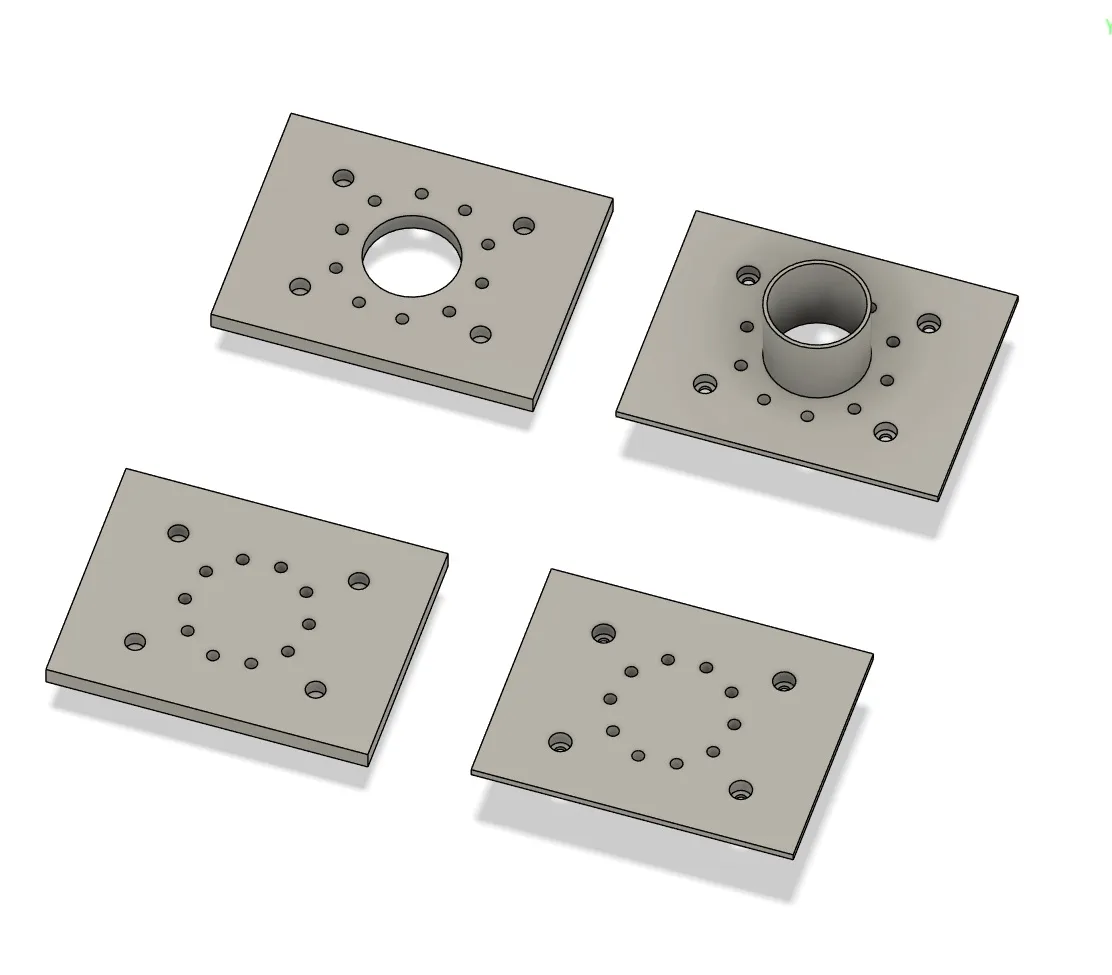 CAD render of four rectangular plates. One carries a raised cylindrical boss, one has the same opening without it, and two are blank. Each has a ring of small vent holes arranged concentrically around the centre, inside four countersunk fastener holes.